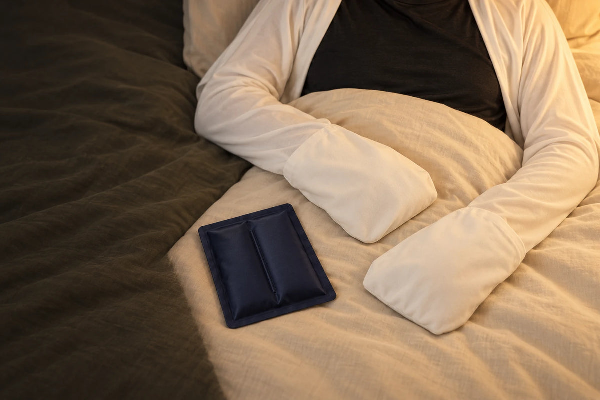 White Noclen-covered hands resting on bedding beside a separate navy cooling pack